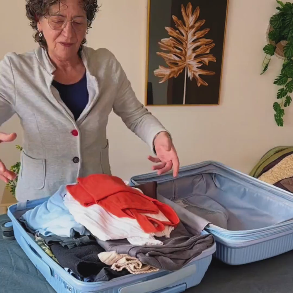 Anwendung: Eine Reisende packt Kleidung ein und komprimiert die Bag mit der Vakuumpumpe.